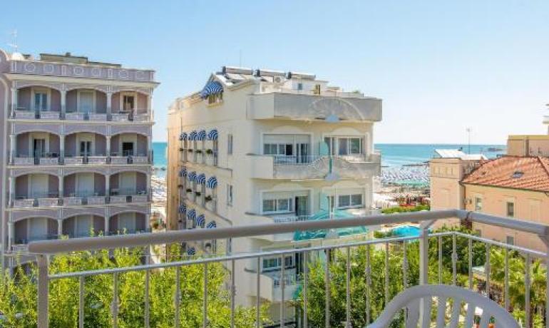 Vista mare da un balcone con sedie bianche.