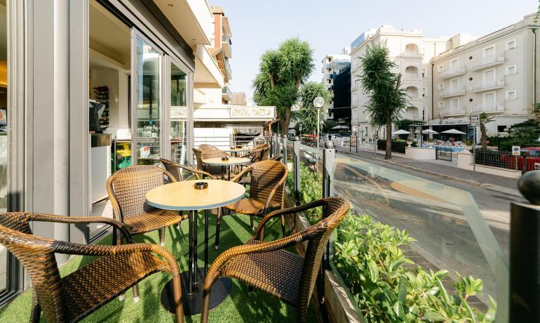 Terrazza con tavoli e sedie in vimini, vista sulla strada.