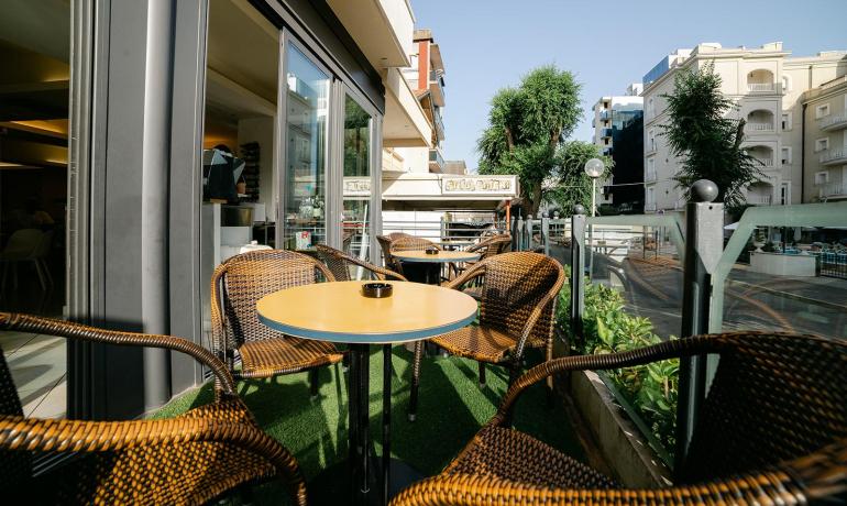 Caffè all'aperto con sedie in vimini e tavolo rotondo.