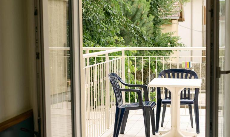 Balcone con sedie e tavolo, vista su alberi.