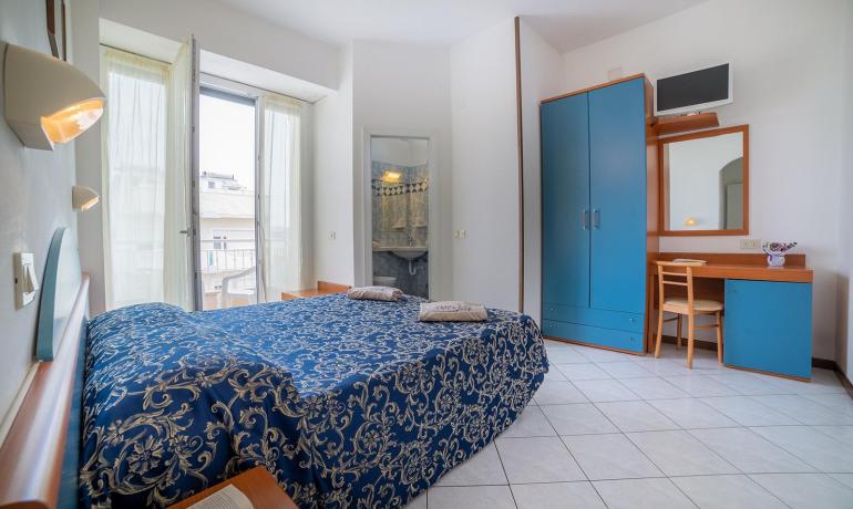 Helles Zimmer mit Doppelbett und blauen Möbeln.