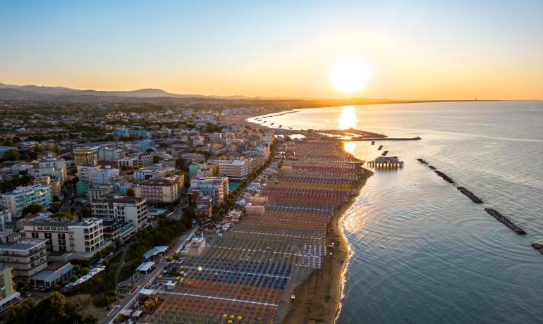 Vista al tramonto di una spiaggia con ombrelloni colorati.