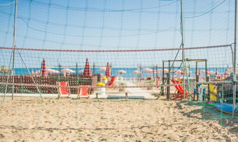Campo da beach volley sulla spiaggia con ombrelloni colorati.